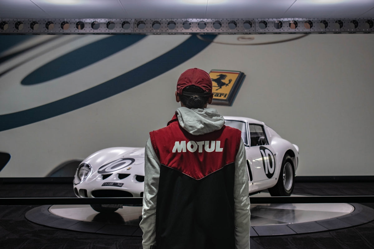 Person in red cap looks at vintage white race car